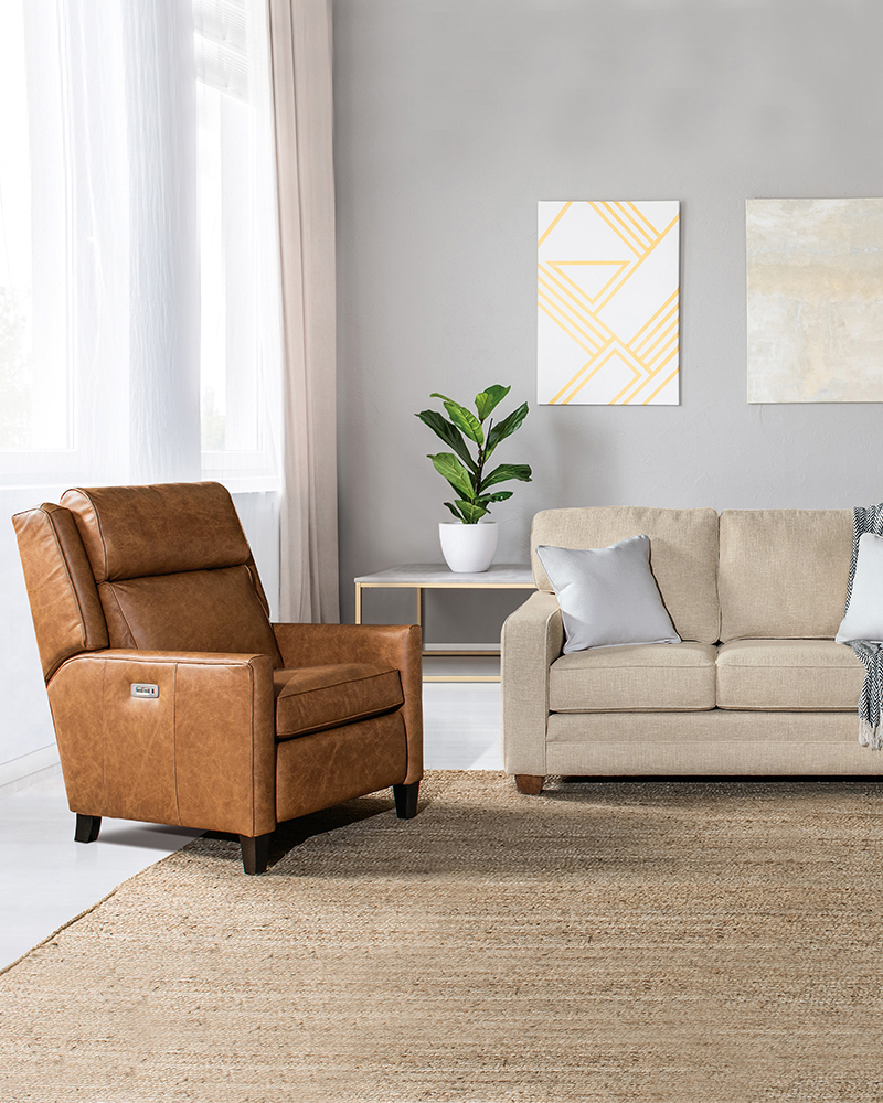 Upholstered living room furniture with leather recliner and beige sofa.