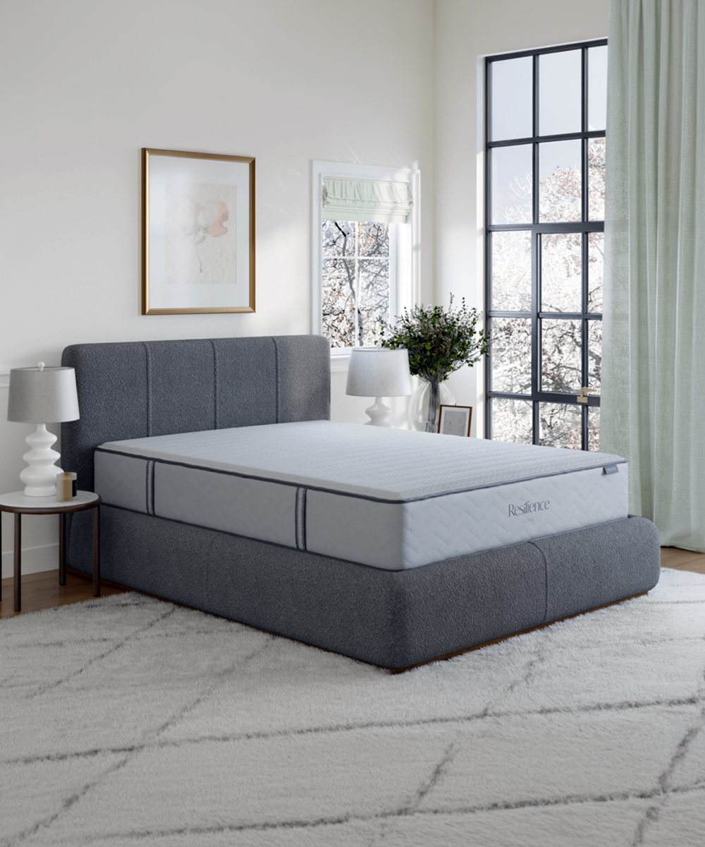 Gray upholstered platform bed with mattress in bright modern bedroom setting