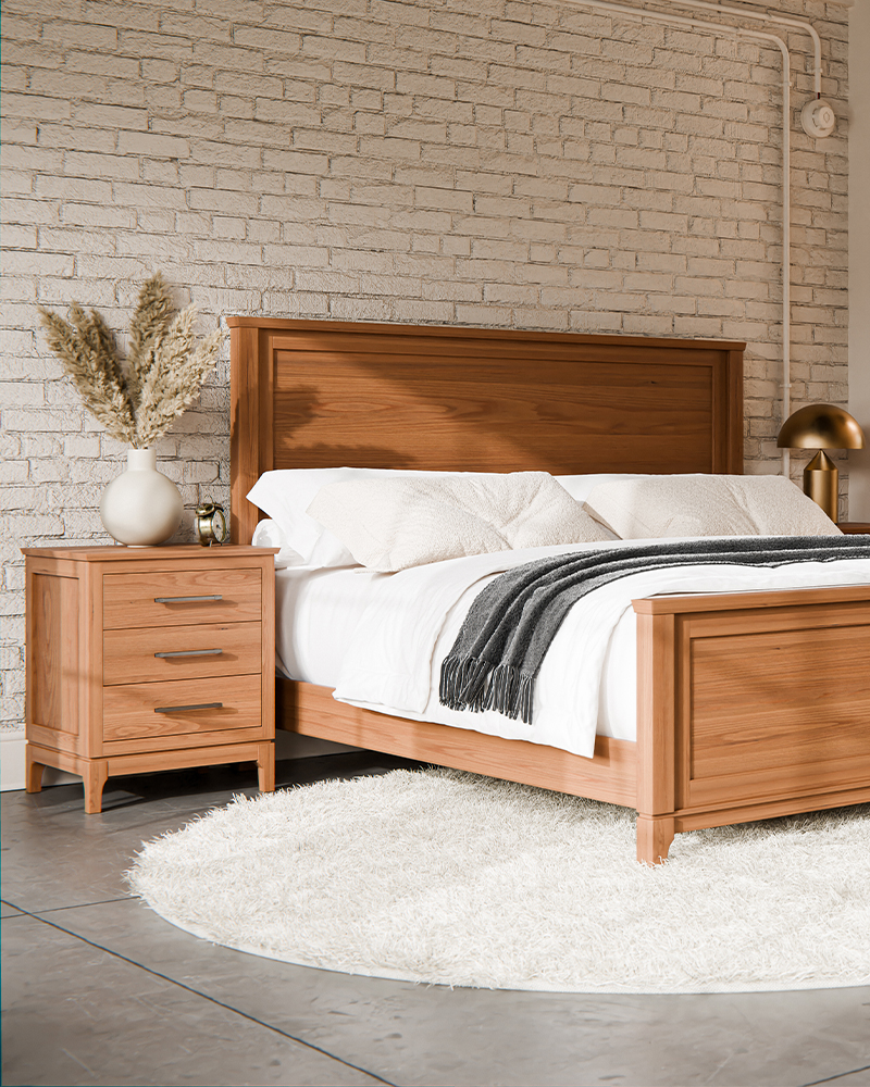 Solid wood Amish nightstand beside a matching bed